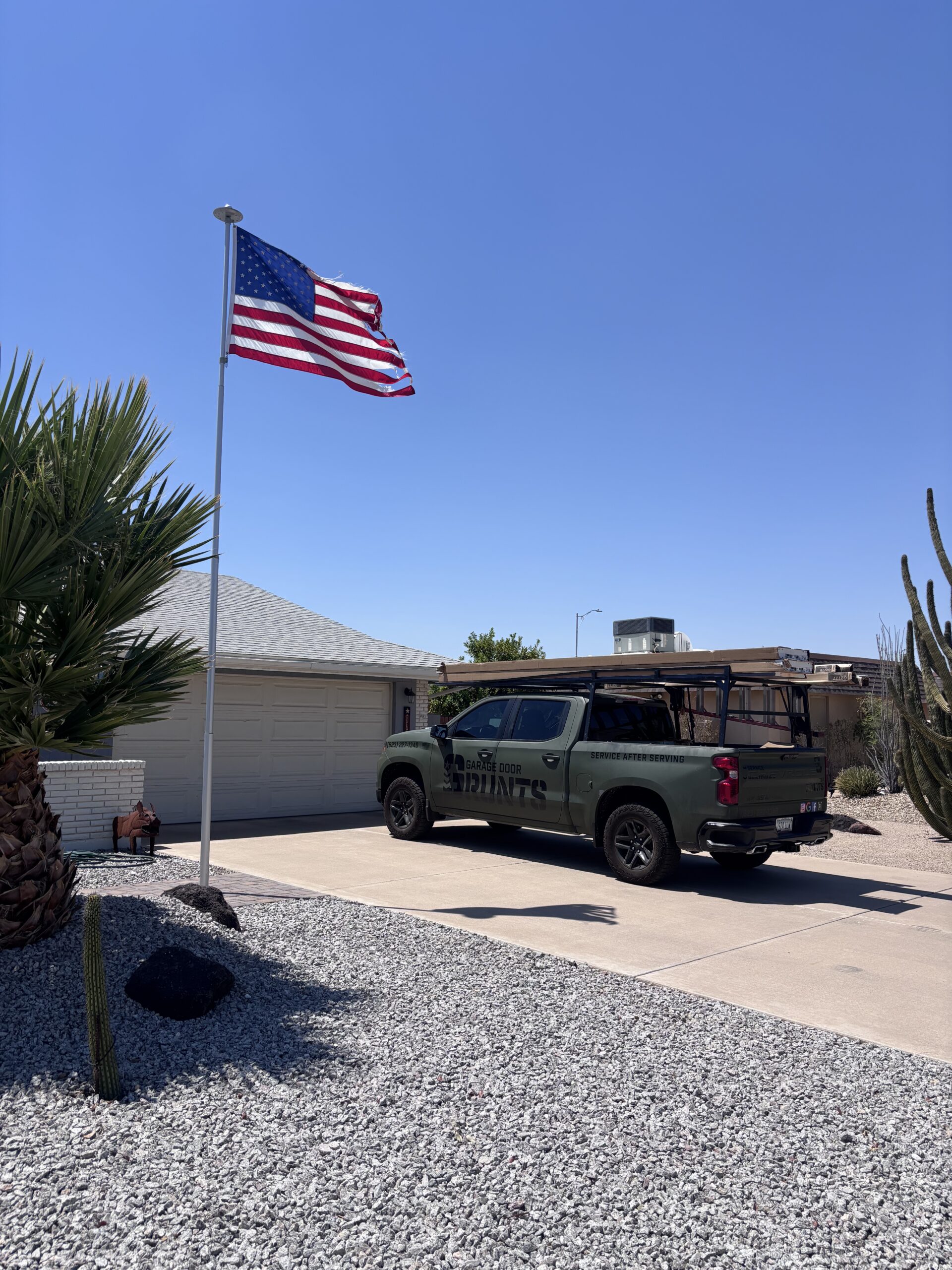 Phoenix Home with Garage Door Grunts repairing a garage door - American Flag flying high in front of residents home