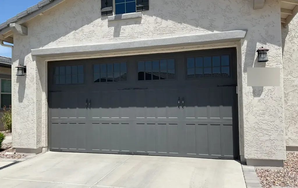 Charcoal short-panel garage door on a white stucco home