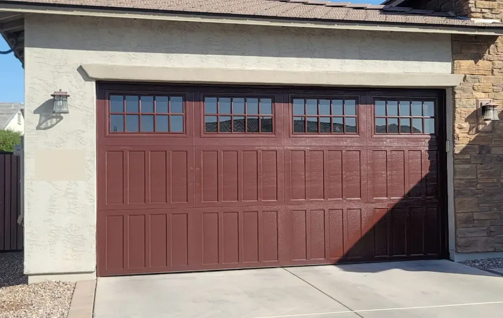 Dark red carriage-style garage door with a row of windows