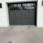 Tall dark carriage-style garage door with a row of windows on a white Paradise Valley home