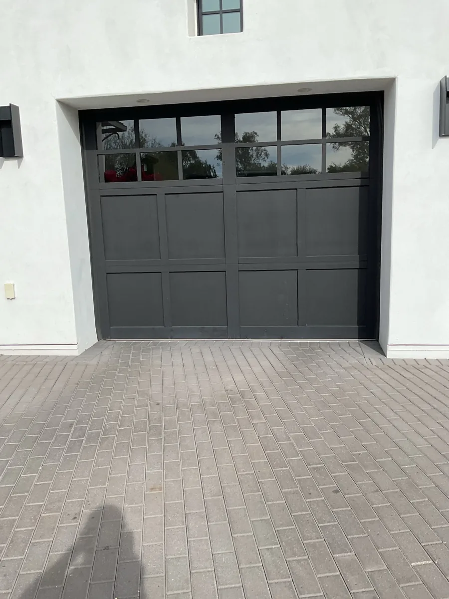 Tall dark carriage-style garage door with a row of windows on a white Paradise Valley home